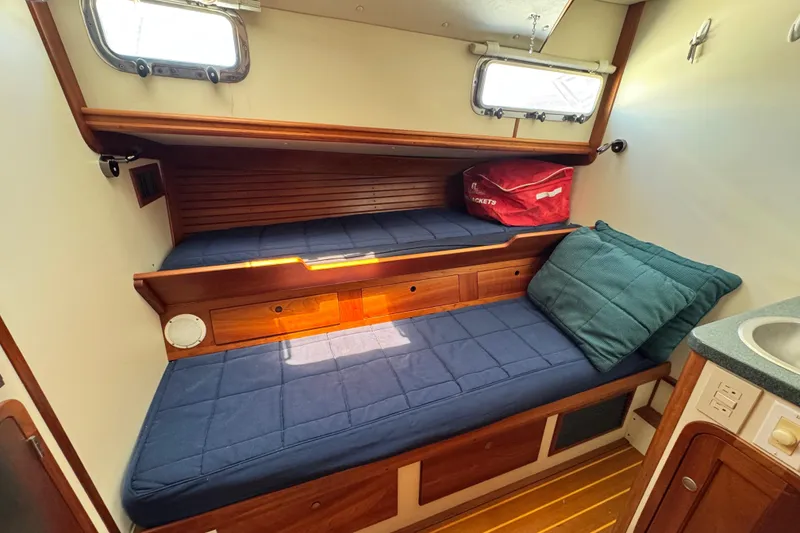 Slide: The Image of 1999 Legacy Yachts 40 Downeast cabin with blue cushions and wooden interior. - 27