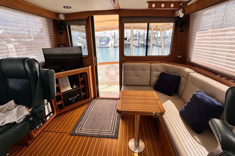 Slide: The Image of Interior of 1999 Legacy Yachts 40 Express with seating, table, and marina view. - 12