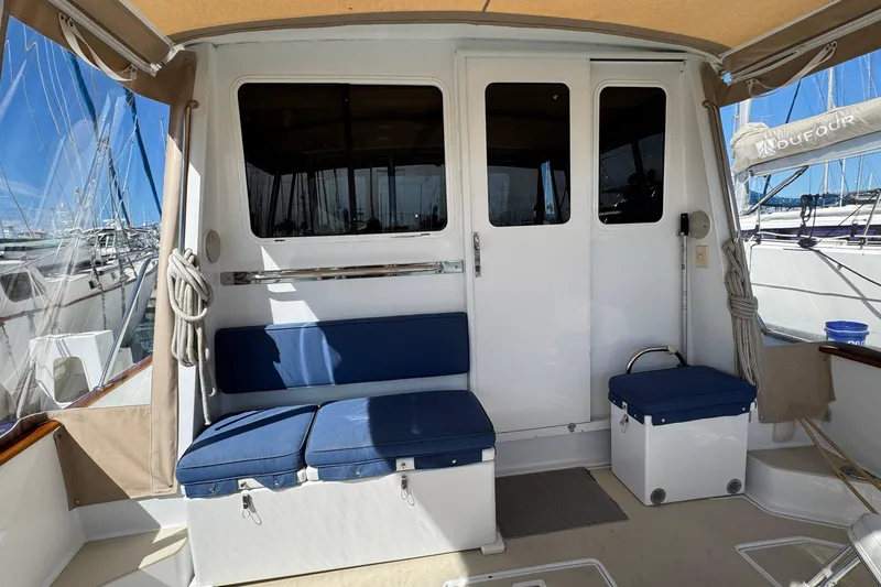 Slide: The Image of 1999 Legacy Yachts 40 Express cockpit with blue cushioned seating and marina view. - 7