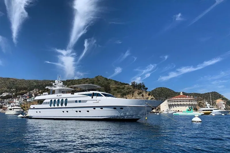 The Image of Monte Fino Eurostyle 1996 yacht anchored in scenic coastal harbor under clear blue sky. - 0