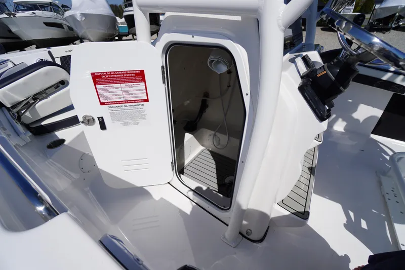 Slide: The Image of 2025 Tidewater 210 LXF boat interior with open storage compartment and safety instructions. - 20