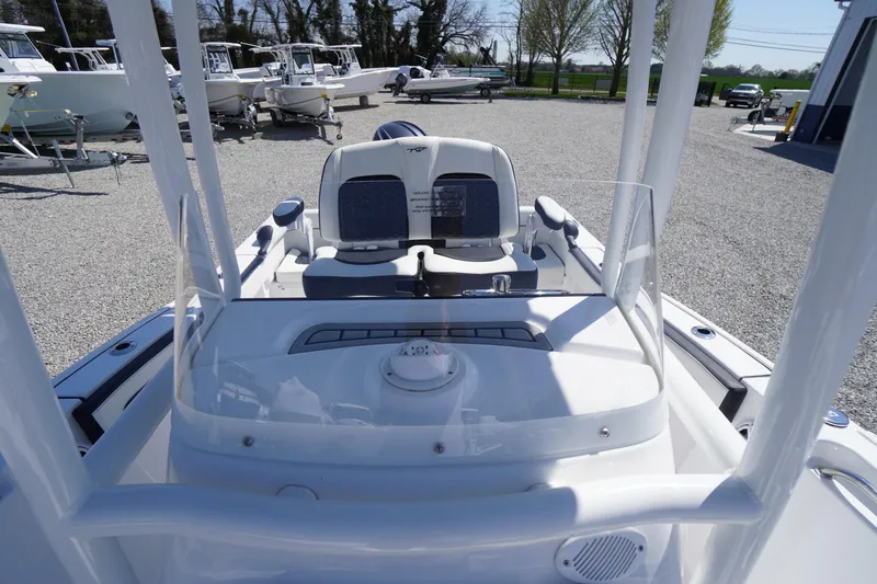 Slide: The Image of 2025 Tidewater 210 LXF boat interior with modern console and seating, parked outdoors. - 28