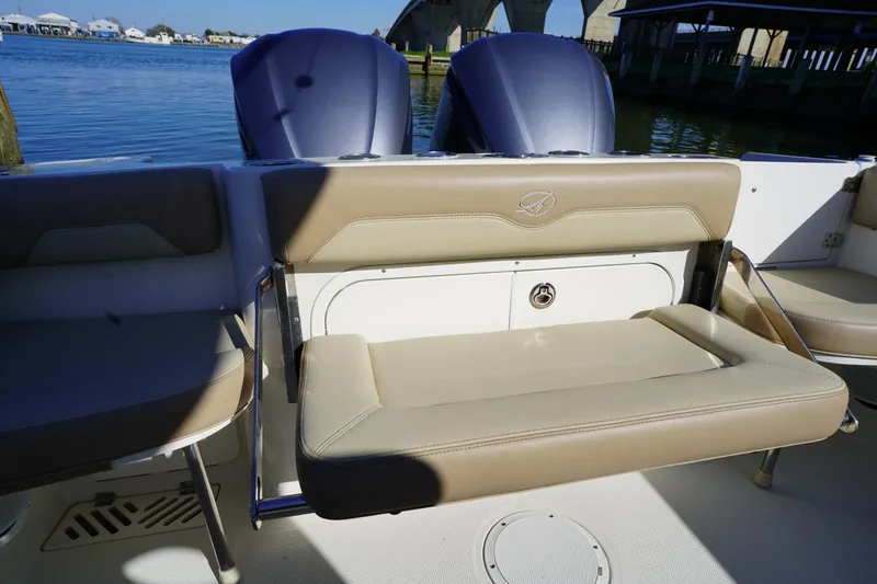 Slide: The Image of 2018 Sailfish 290 CC boat with beige seating, dual engines, and waterfront view. - 11