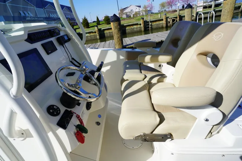 Slide: The Image of 2018 Sailfish 290 CC boat cockpit with steering wheel and beige seating. - 3