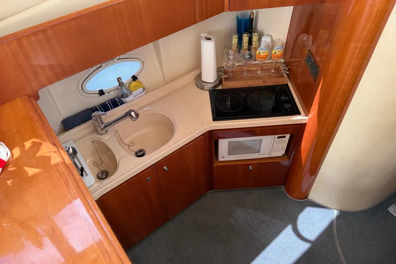 Slide: The Image of 2004 Azimut 39E yacht kitchen with sink, stove, microwave, and wooden cabinetry. - 16