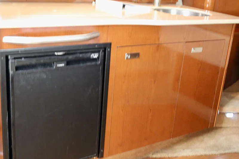 Slide: The Image of 2011 Sea Ray Sundancer 350 interior kitchen with wood cabinetry and compact refrigerator. - 26