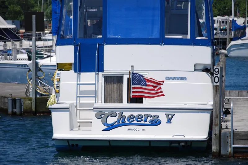 Slide: The Image of 1994 Carver 390 Cockpit Motor Yacht docked, displaying American flag and "Cheers V" name. - 1