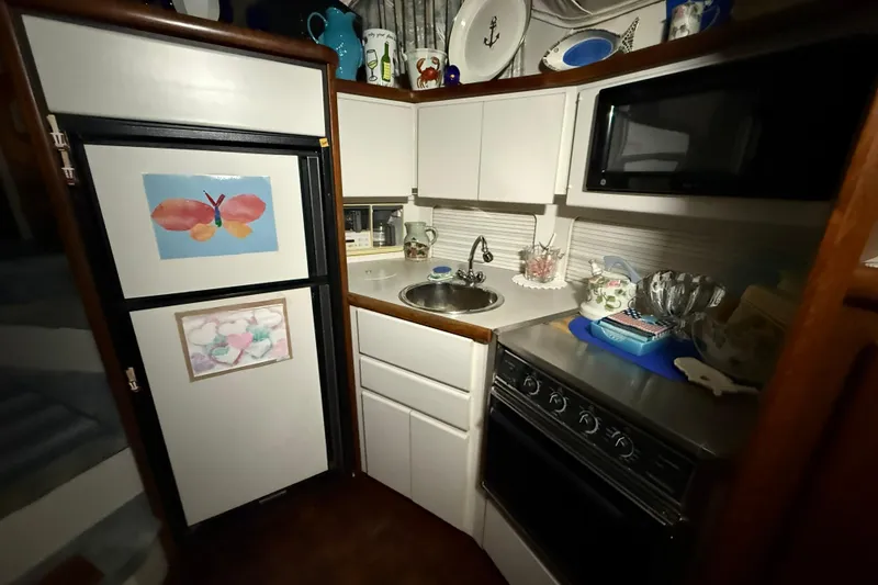 Slide: The Image of Compact kitchen in a 1994 Carver 390 Cockpit Motor Yacht with appliances and decor. - 12