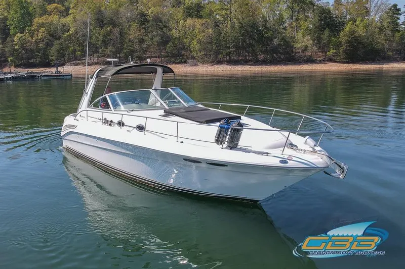 Slide: The Image of 2000 Sea Ray 340 Sundancer cruising on a serene lake with forested shoreline. - 10