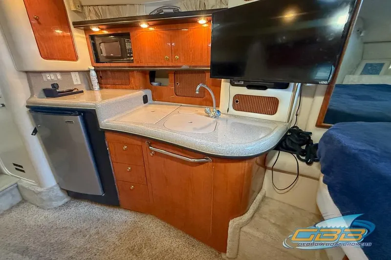 Slide: The Image of Interior of 2000 Sea Ray 340 Sundancer with kitchenette and TV setup. - 16