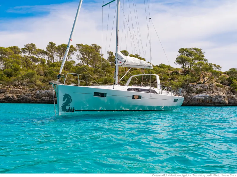 Slide: The Image of 2017 Beneteau Oceanis 41.1 sailboat on turquoise water near coastal landscape. - 12