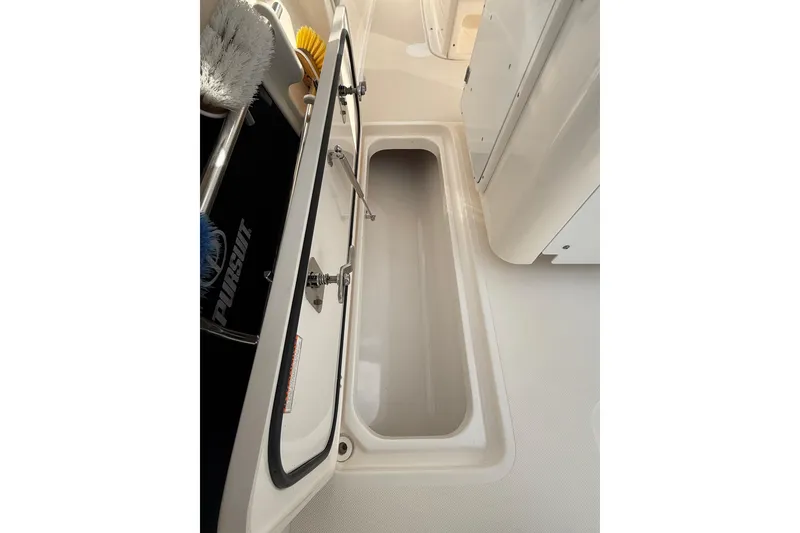 Slide: The Image of Open storage compartment on 2016 Pursuit S 280 Sport boat, featuring cleaning brushes. - 30