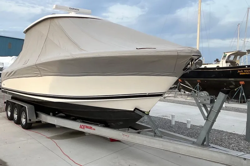 Slide: The Image of 2016 Pursuit S 280 Sport boat covered on trailer, dockside setting. - 50