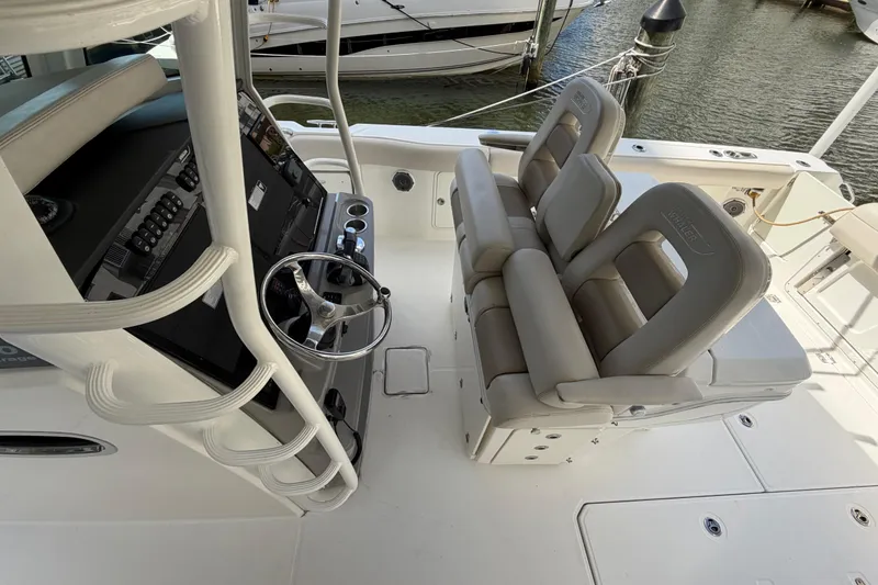 Slide: The Image of 2016 Boston Whaler 330 Outrage helm with dual seats and steering wheel, docked by water. - 14