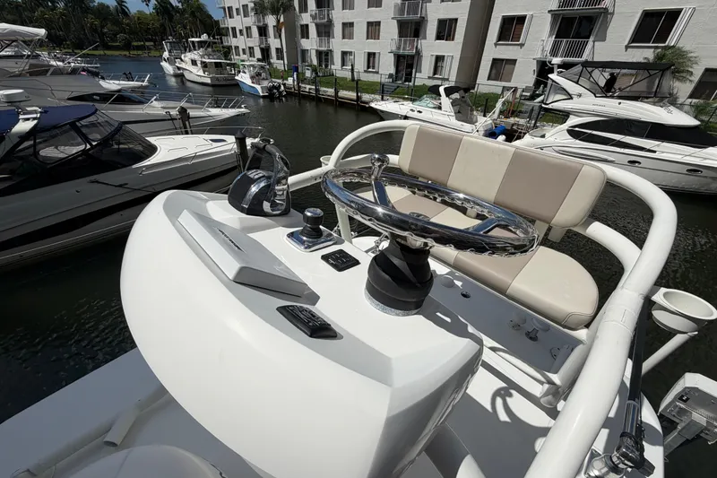 Slide: The Image of Boston Whaler 330 Outrage 2016 helm with steering wheel and controls, docked among other boats. - 23