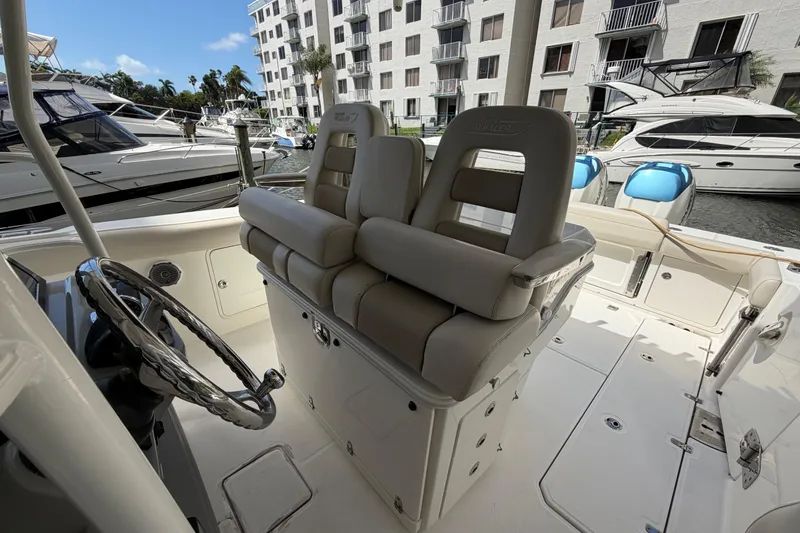 Slide: The Image of 2016 Boston Whaler 330 Outrage boat interior with helm seating and marina view. - 24