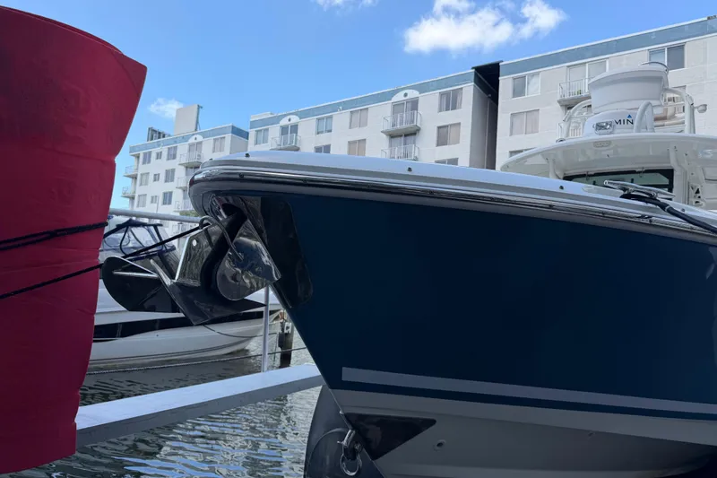 Slide: The Image of 2016 Boston Whaler 330 Outrage docked near waterfront buildings under blue sky. - 6