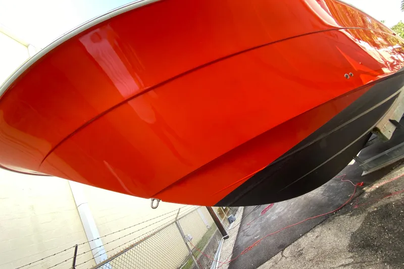 Slide: The Image of 2006 Hydra-Sports Vector 3300 CC boat with vibrant orange hull, docked outdoors. - 20