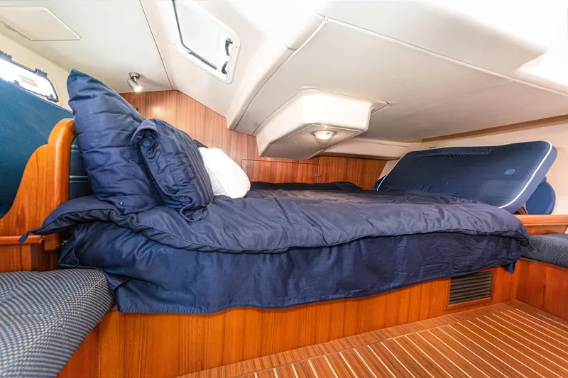 Slide: The Image of Cozy cabin interior of 2007 Hunter 38 sailboat with wooden paneling and blue bedding. - 46