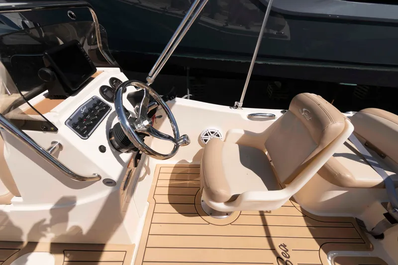 Slide: The Image of 2023 Scout 175 Sportfish boat interior with steering wheel and beige seating. - 7