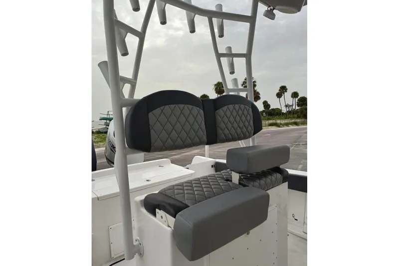 Slide: The Image of 2024 Clearwater 2500 boat seating with diamond-stitched upholstery and rod holders, parked near palm trees. - 3