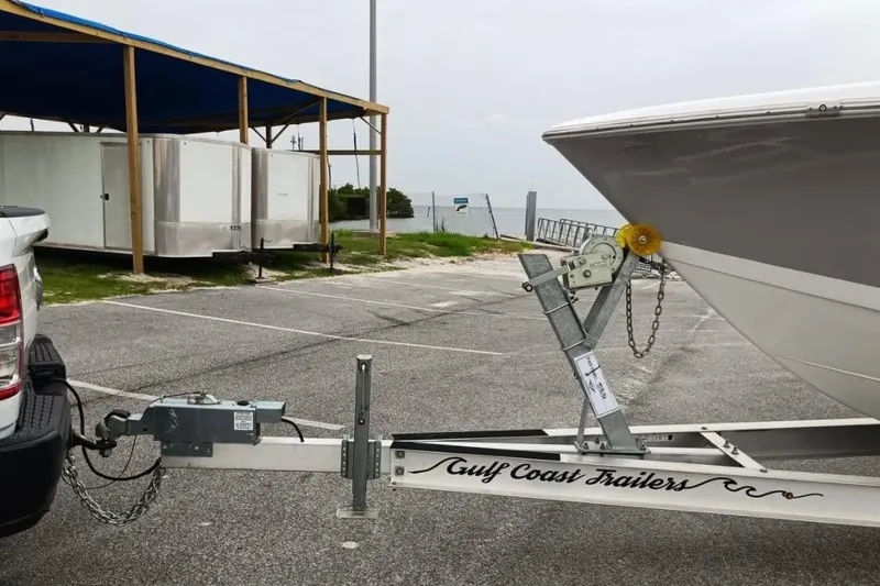 Slide: The Image of Trailer hitching a 2024 Clearwater 2500 boat at a parking area near the coast. - 8