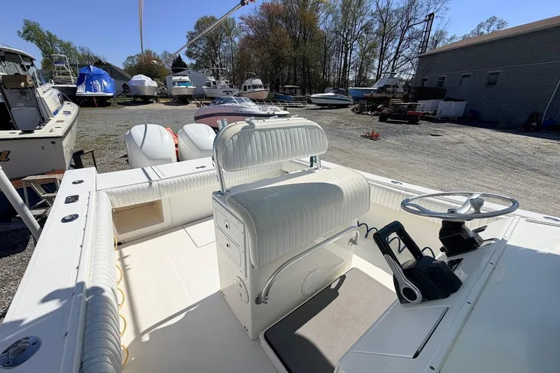 Slide: The Image of 2006 Regulator 29 Forward Seating boat interior with steering wheel and seating, in a boatyard. - 12