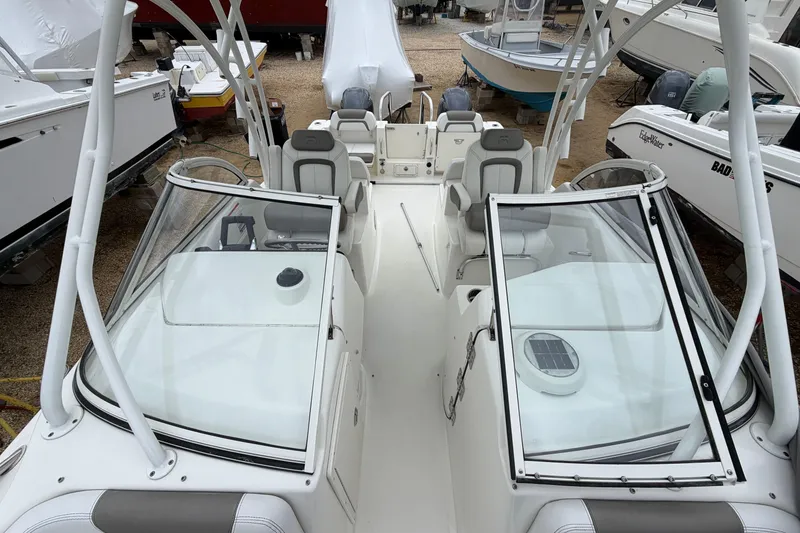 Slide: The Image of 2019 World Cat 255 DC boat interior with seating and windshield, docked among other boats. - 13