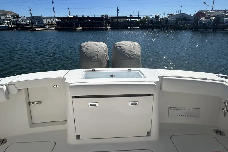 Slide: The Image of 2018 Albemarle 29 Express boat stern view with covered engines and marina backdrop. - 12