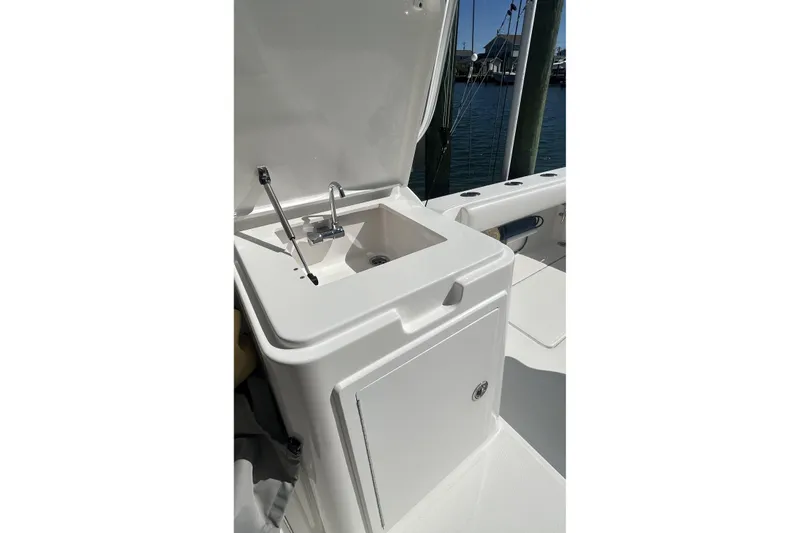 Slide: The Image of 2018 Albemarle 29 Express boat sink and storage area, docked by the water. - 22