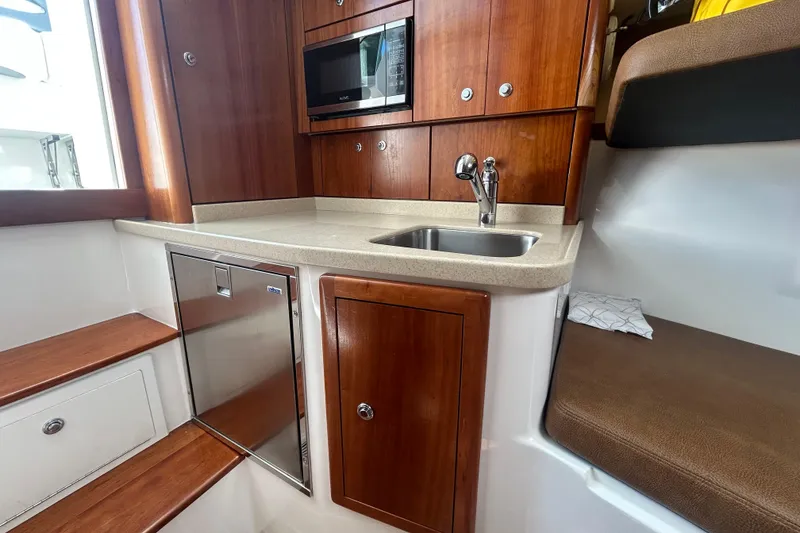 Slide: The Image of 2018 Albemarle 29 Express boat interior with kitchenette, sink, and wooden cabinetry. - 49