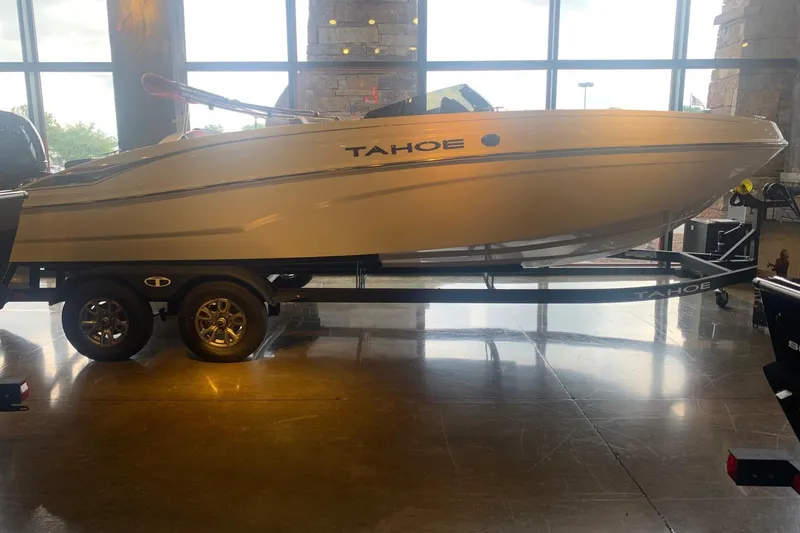 The Image of 2026 Tahoe T21 boat on trailer in showroom with large windows. - 0