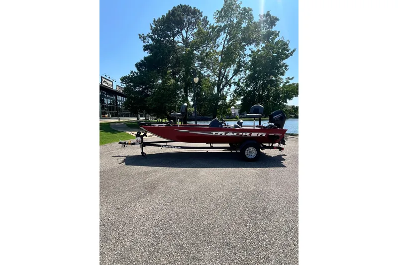 The Image of 2026 Tracker Pro 170 boat in red, parked outdoors near trees and water. - 0