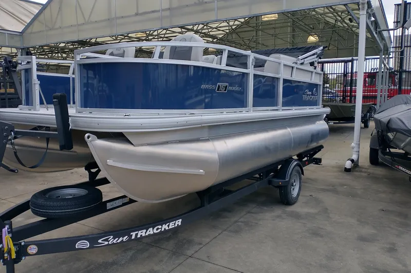 Slide: The Image of 2026 Sun Tracker Bass Buggy 16 XL Select pontoon boat on trailer in showroom. - 3