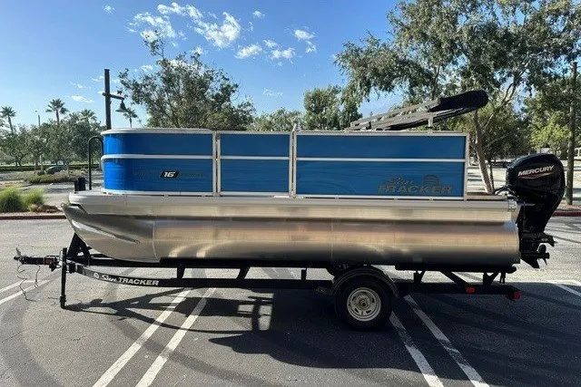The Image of 2026 Sun Tracker Party Barge 16 DLX pontoon boat on trailer in sunny parking lot. - 0