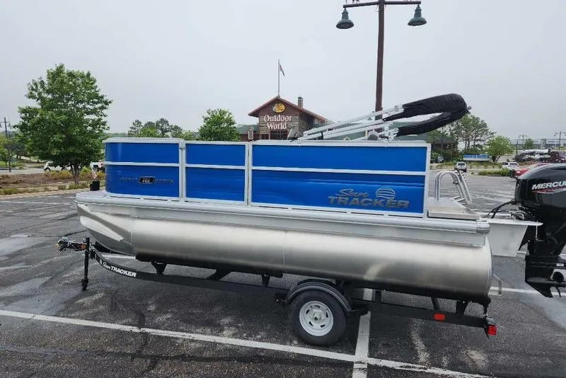 Slide: The Image of 2026 Sun Tracker Party Barge 16 DLX pontoon boat on trailer in parking lot. - 1