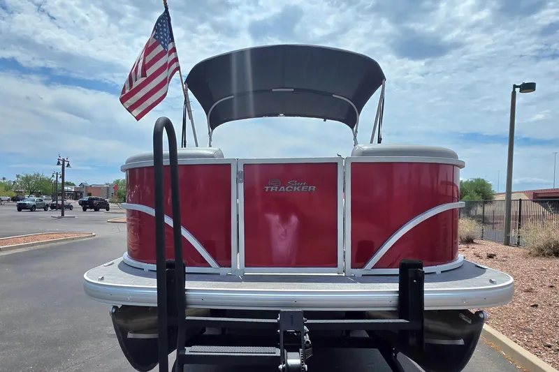 Slide: The Image of 2026 Sun Tracker Party Barge 20 DLX pontoon boat with American flag, parked outdoors. - 2