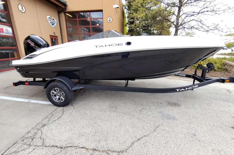 Slide: The Image of 2026 Tahoe T18 boat on trailer, parked outside a building. - 0