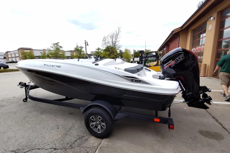 Slide: The Image of 2026 Tahoe T18 boat with Mercury engine on trailer, parked outside a building. - 3