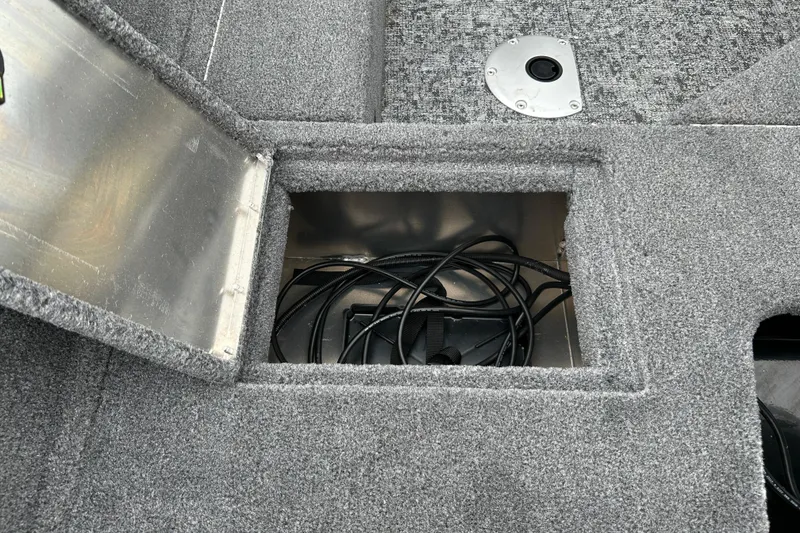 Slide: The Image of Storage compartment in 2026 Tracker Pro Guide V-16 SC boat, featuring cables and carpeted interior. - 6