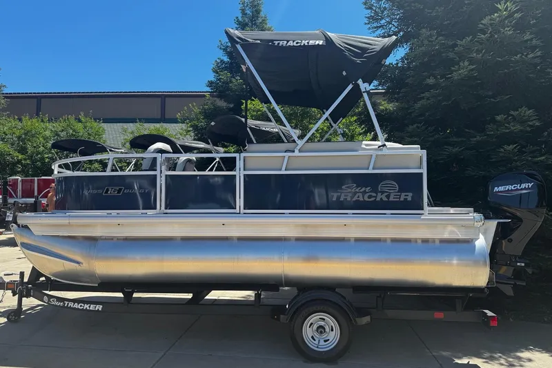 The Image of 2026 Sun Tracker Bass Buggy 16 XL Select pontoon boat with Mercury engine, parked outdoors. - 0