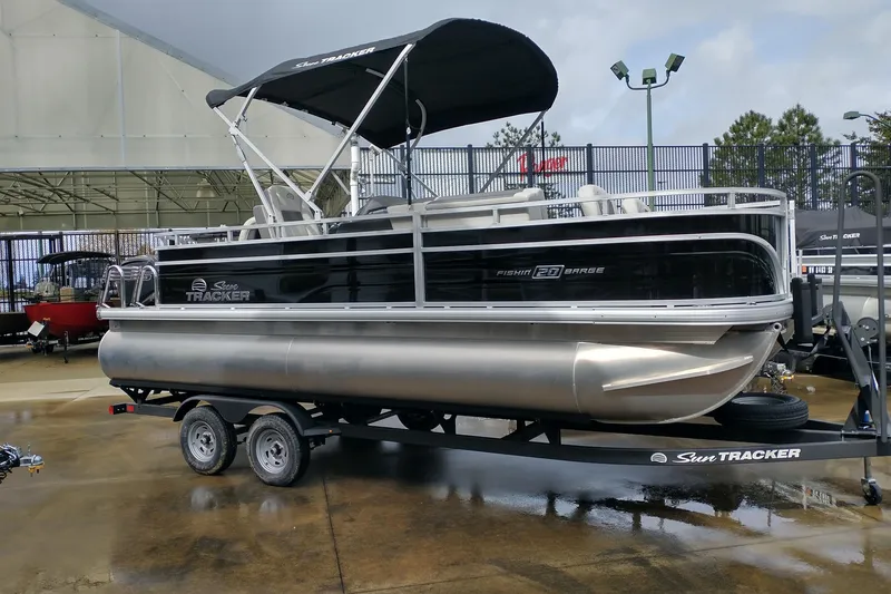 The Image of 2026 Sun Tracker Fishin' Barge 20 DLX pontoon boat on trailer, outdoor display. - 0