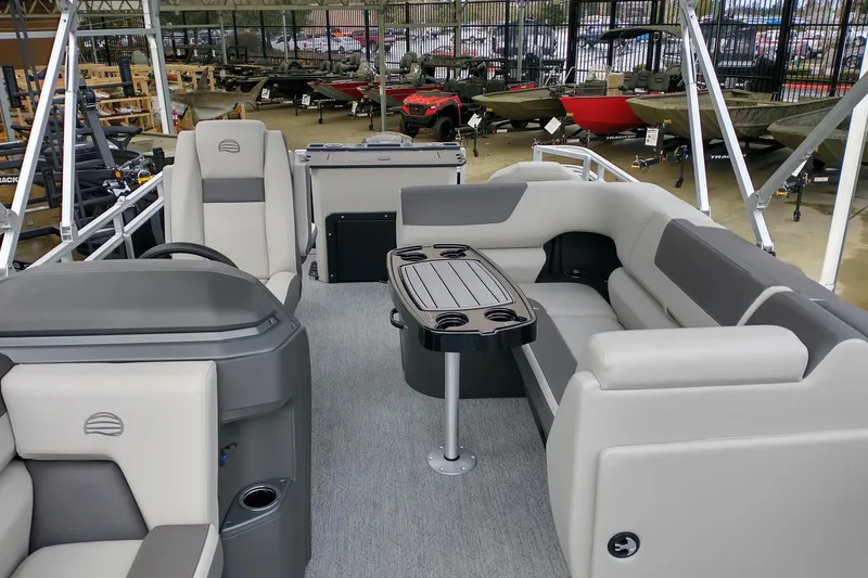 Slide: The Image of 2026 Sun Tracker Fishin' Barge 20 DLX interior with seating and table, displayed in showroom. - 11