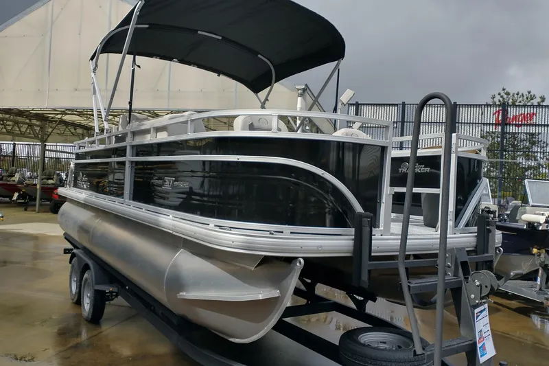 Slide: The Image of 2026 Sun Tracker Fishin' Barge 20 DLX pontoon boat on trailer, outdoor display. - 2