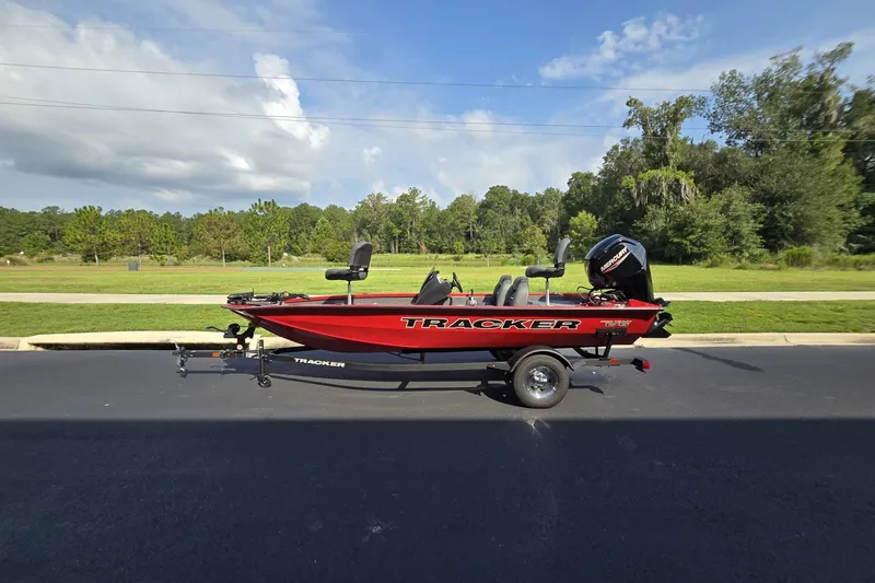 The Image of 2026 Tracker Pro Team 175 boat on trailer, parked on asphalt, with lush greenery background. - 0