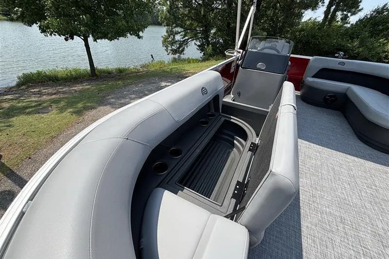 Slide: The Image of 2026 Sun Tracker Party Barge 16 DLX interior with seating and storage, near a scenic lake. - 9
