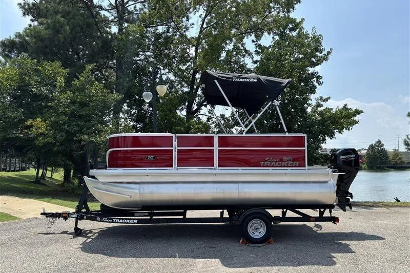 The Image of 2026 Sun Tracker Party Barge 16 DLX pontoon boat on trailer by a lake. - 0