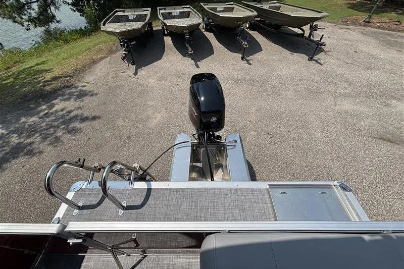 Slide: The Image of 2026 Sun Tracker Party Barge 16 DLX with motor, parked near small boats. - 19