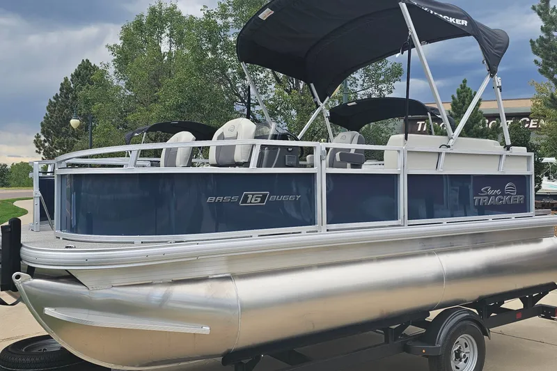 The Image of 2026 Sun Tracker Bass Buggy 16 XL Select pontoon boat with canopy, parked outdoors. - 0