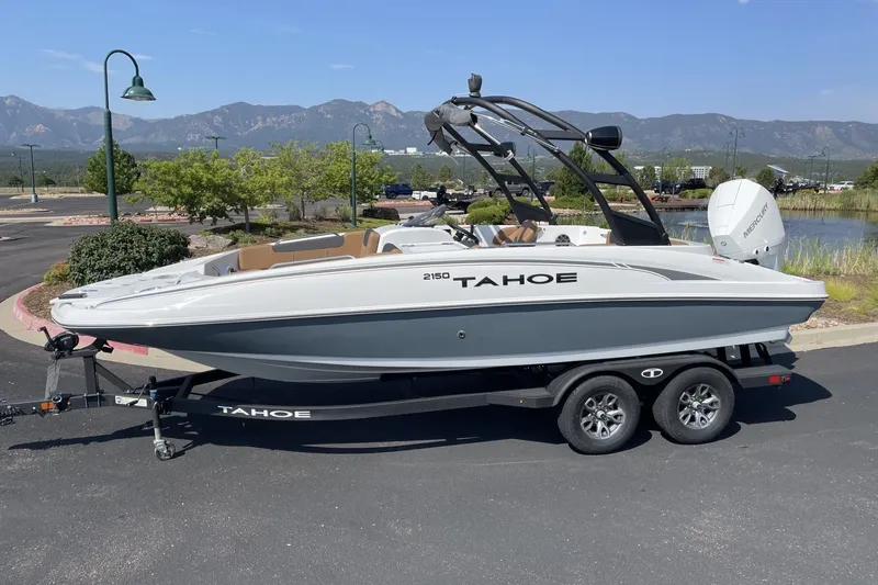 The Image of 2026 Tahoe 2150 boat on trailer, parked outdoors with scenic mountain backdrop. - 0